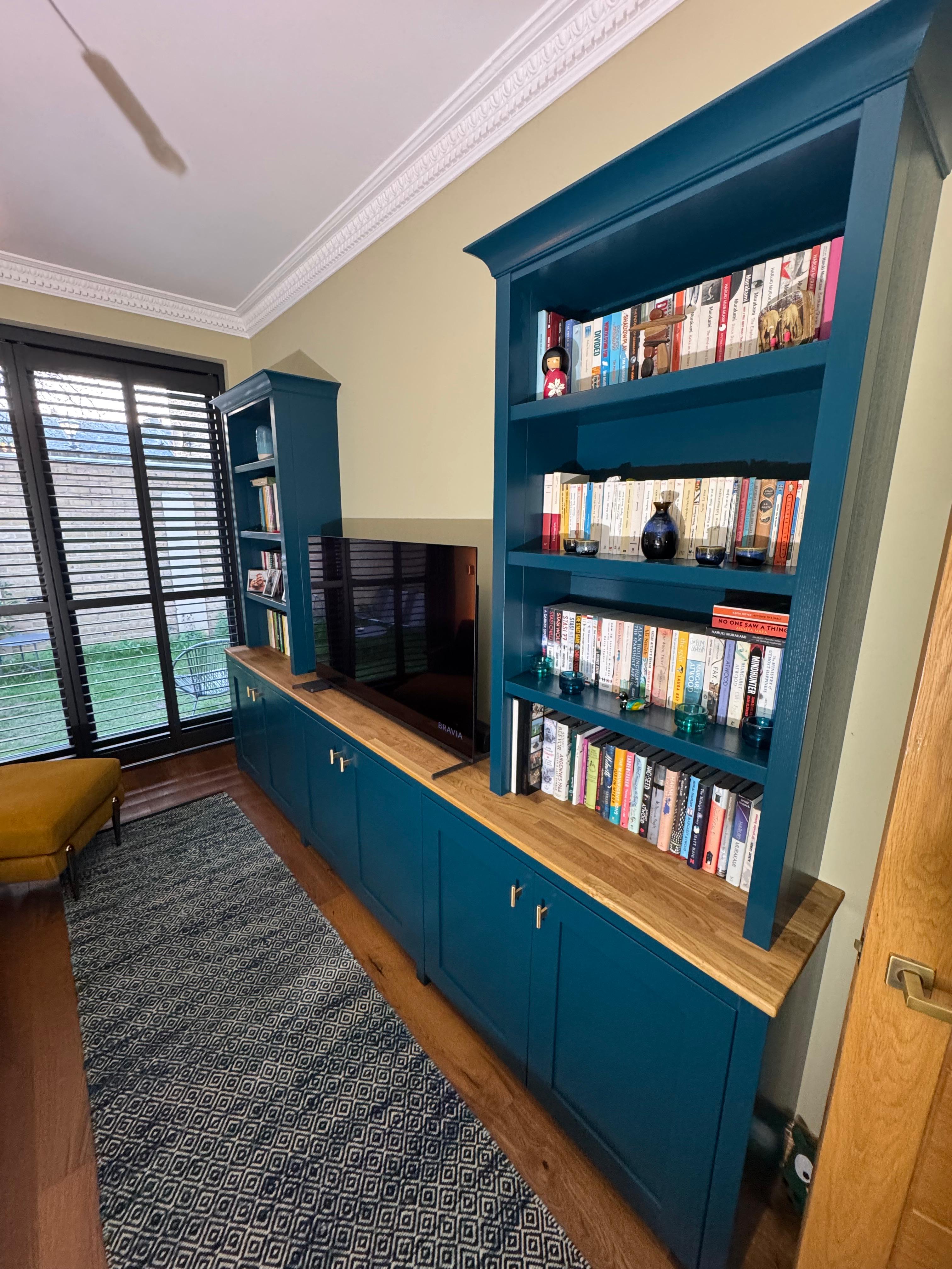 Teal painted built-in bookshelf and media unit with oak shelving