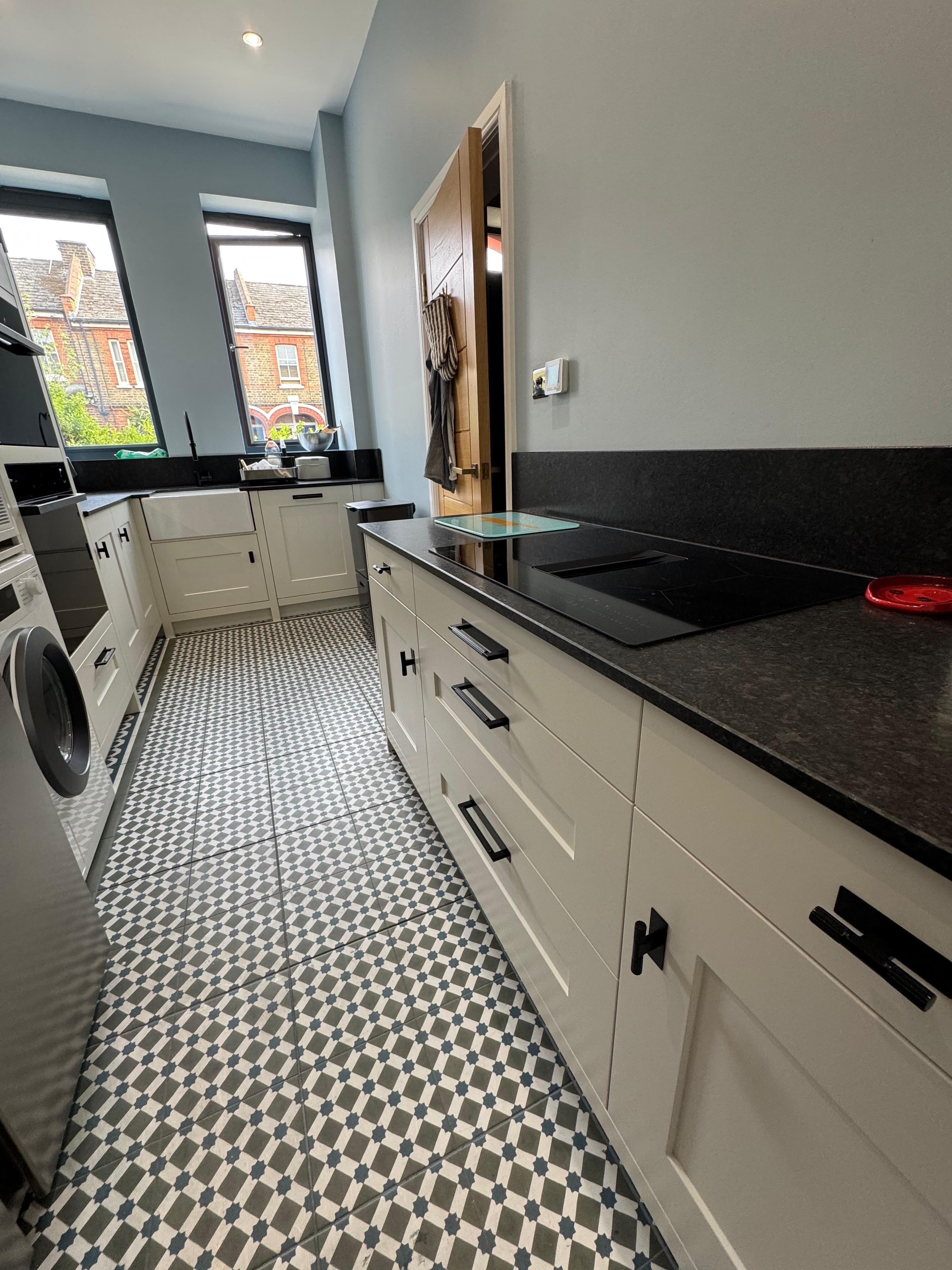 White galley kitchen with black countertops and geometric floor tiles