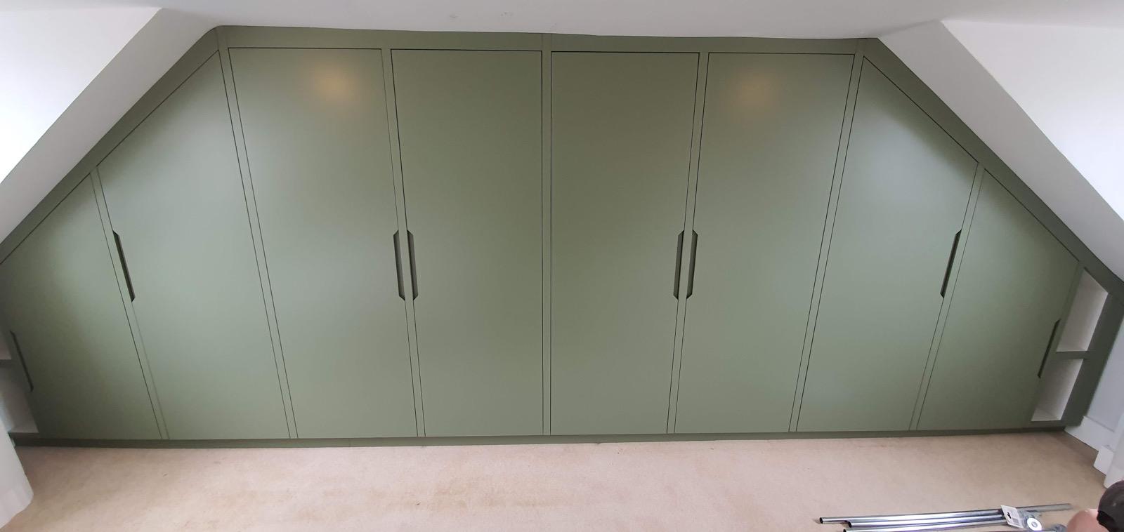 Sage green fitted wardrobes in attic space