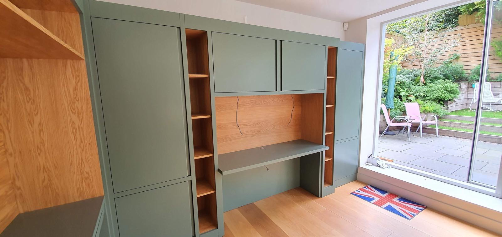 Sage green home office unit with oak interior and desk area